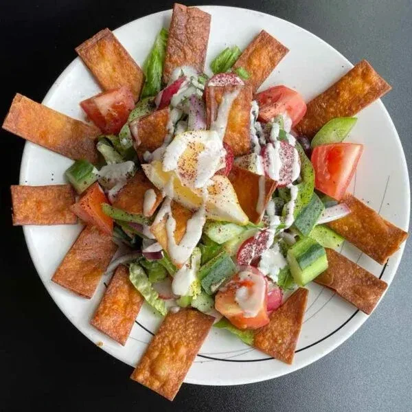 Vibrant Mediterranean salad with vegetables, creamy dressing, and crispy pita chips.
