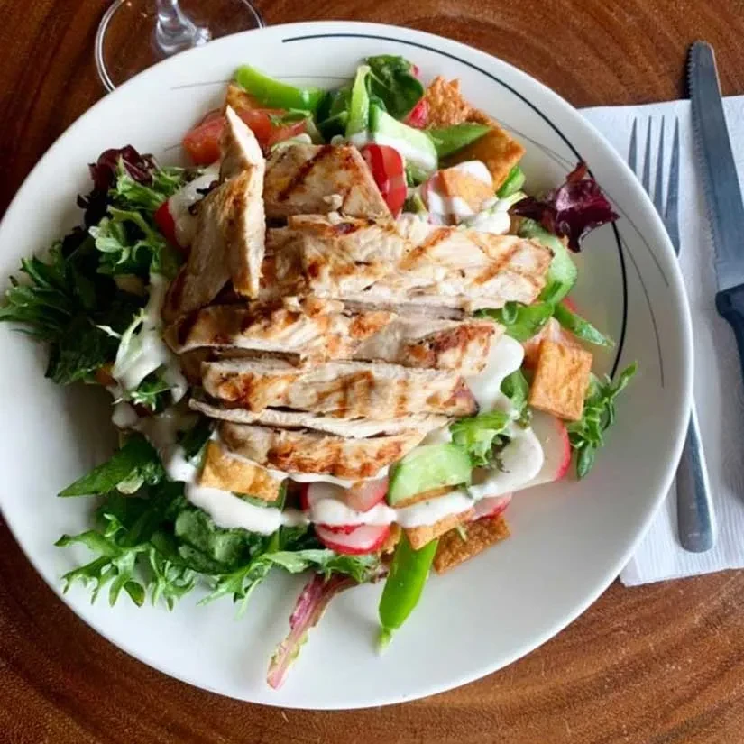 Grilled chicken salad with fresh greens, vegetables, and dressing.