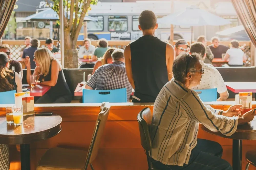 Sunlit outdoor patio with people dining and socializing.