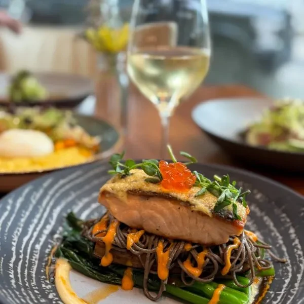 Perfectly seared salmon fillet with roe, microgreens, noodles, and asparagus.