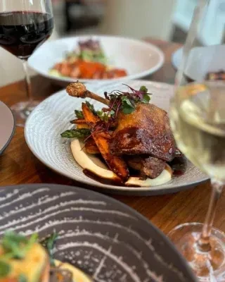 Roasted duck leg on purée with vegetables and wine in a restaurant.