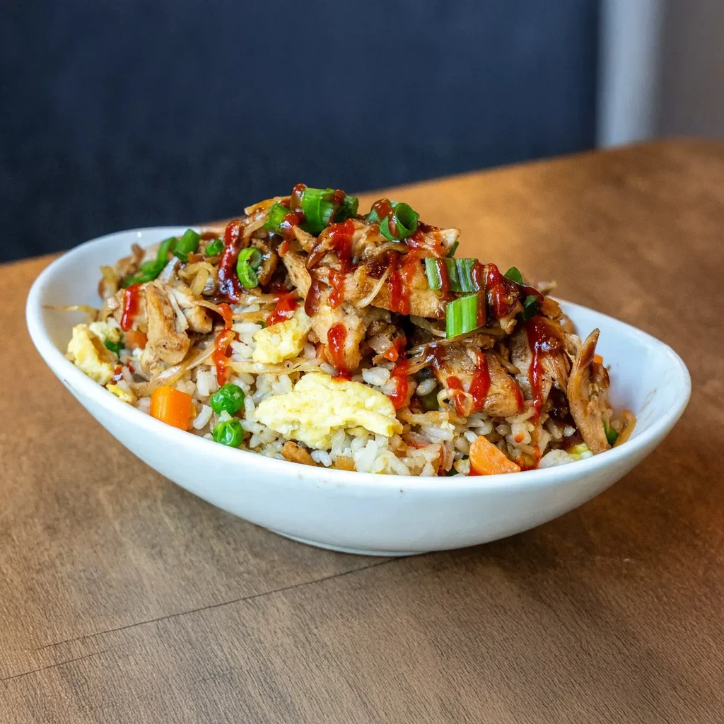 Fried rice with chicken, egg, peas, carrots, sauce, green onions.
