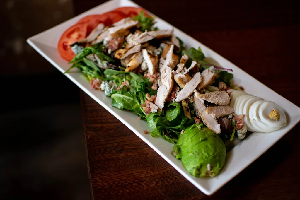 Grilled chicken salad with blue cheese, bacon, avocado, egg, tomato.