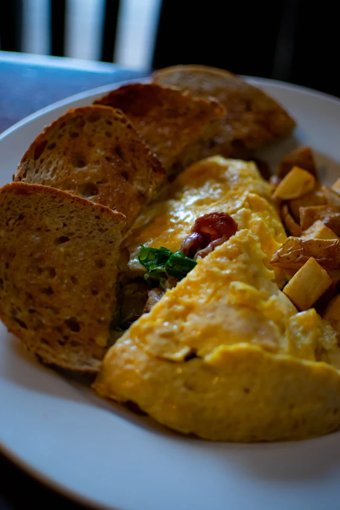 Close-up of a golden omelet, toast, and pan-fried potatoes.