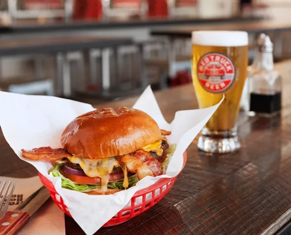 Bacon cheeseburger in red basket, Red Truck Beer on wood table.
