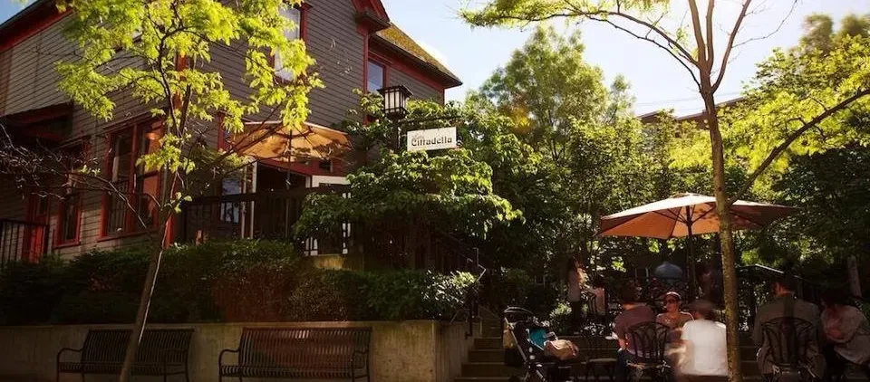 Cittadella restaurant exterior with outdoor dining area, people, and green foliage.