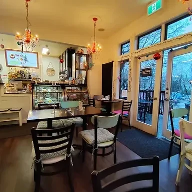 Empty, warmly lit cafe interior with counter, tables, and ornate chandeliers.