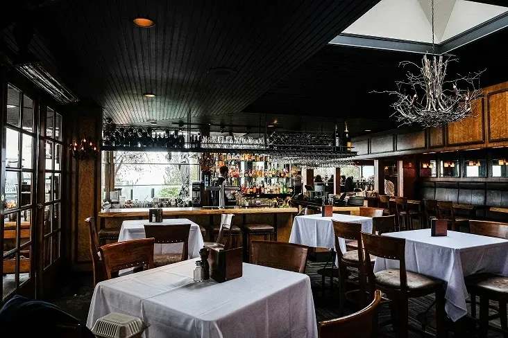 Elegant restaurant interior with dining tables, illuminated bar, and artistic chandelier.