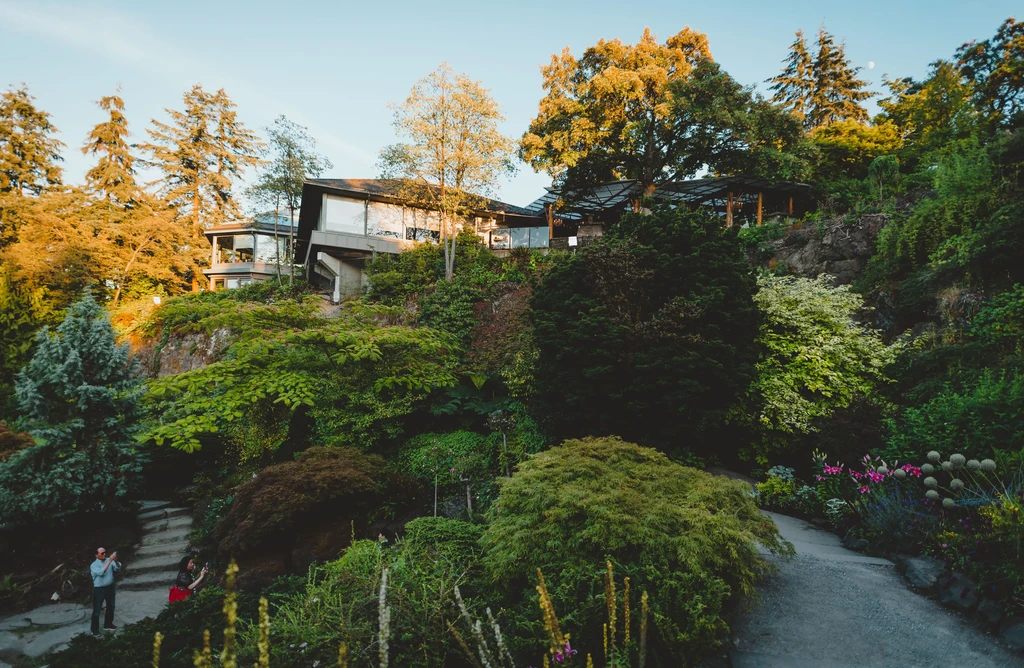 Modern building nestled in a lush hillside garden at golden hour.