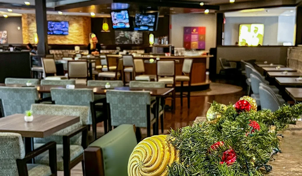 Modern restaurant bar interior, Christmas decorated, with empty tables and TVs.