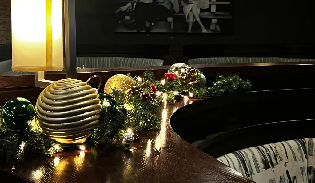 Warmly lit holiday garland on a restaurant's polished wooden bar.