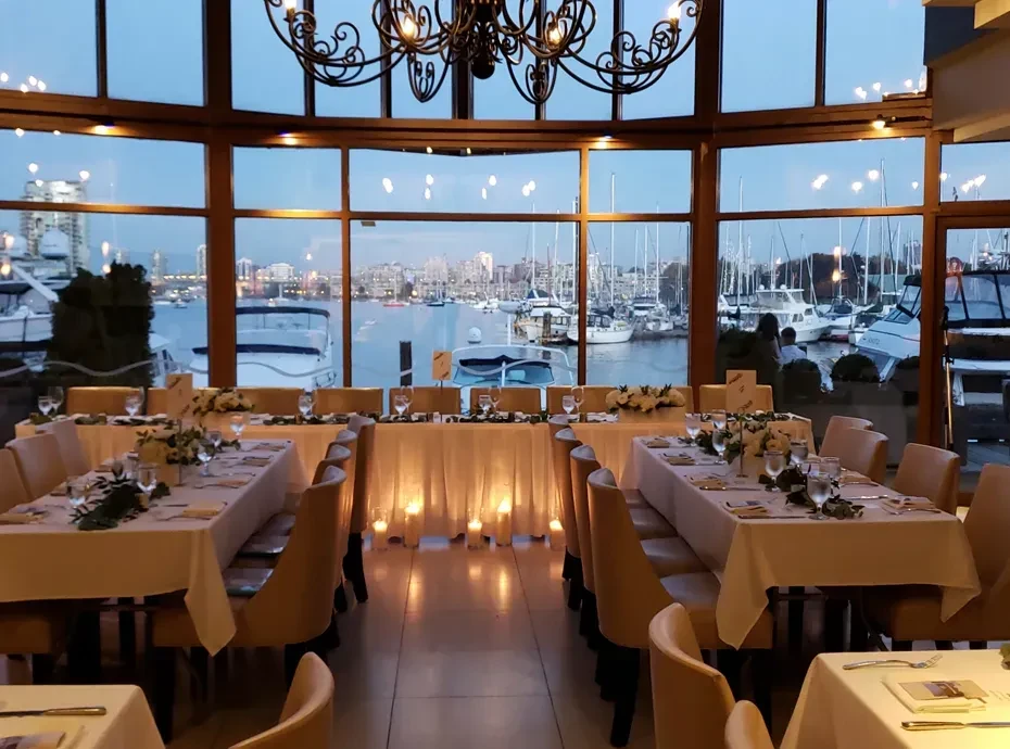 Refined dining room overlooks a marina and city skyline at twilight.