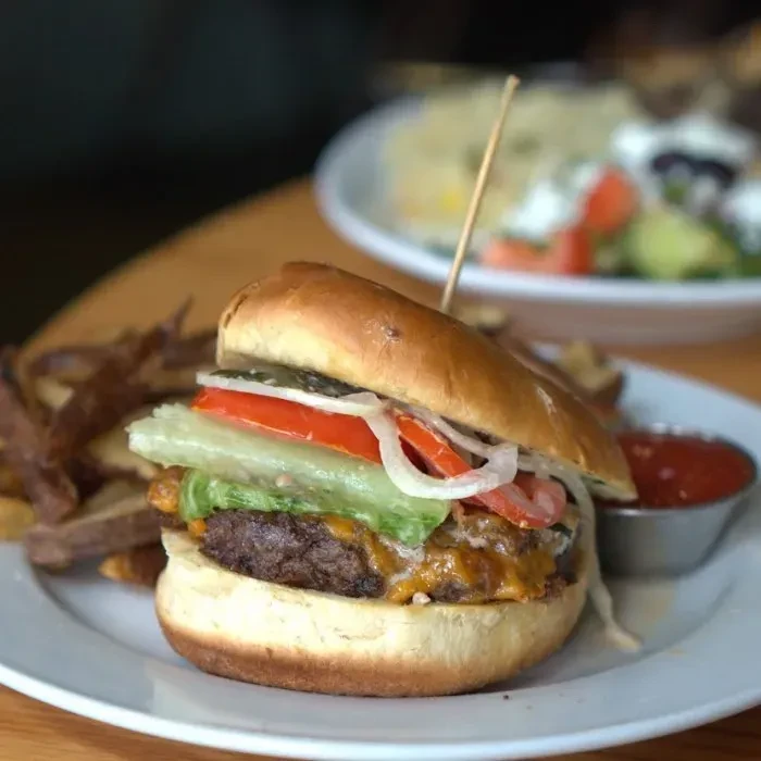 Close-up of a gourmet cheeseburger with fries and ketchup on a plate.