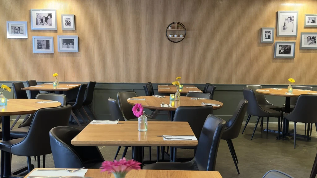 Empty modern restaurant featuring light wood tables and two-toned walls.