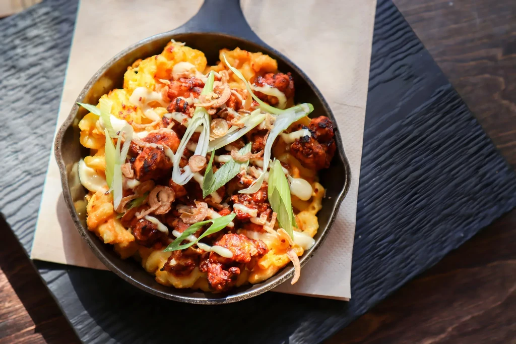 Skillet mac and cheese with chicken, sauce, green onions, and fried shallots.