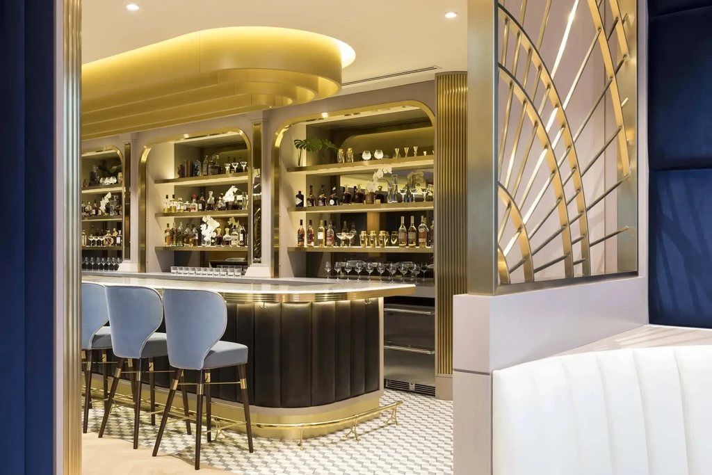 High-end restaurant bar with stocked shelves, velvet stools, and gold accents.