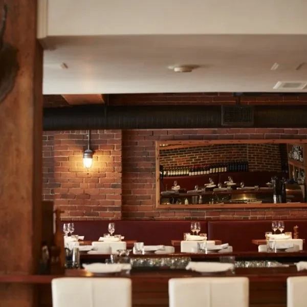 Modern industrial restaurant interior with set tables and brick wall.