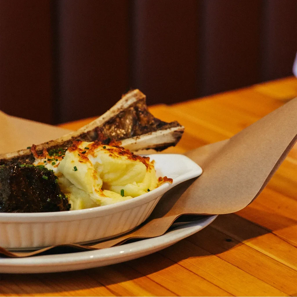 Braised short rib and crisped mashed potatoes garnished with green herbs.
