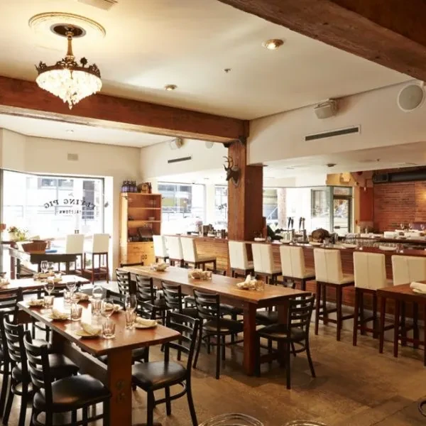 Empty gastropub interior with tables, bar, and reflected "FAT PIG GASTOWN".