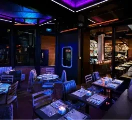 Modern, empty restaurant interior with purple and blue neon lights.