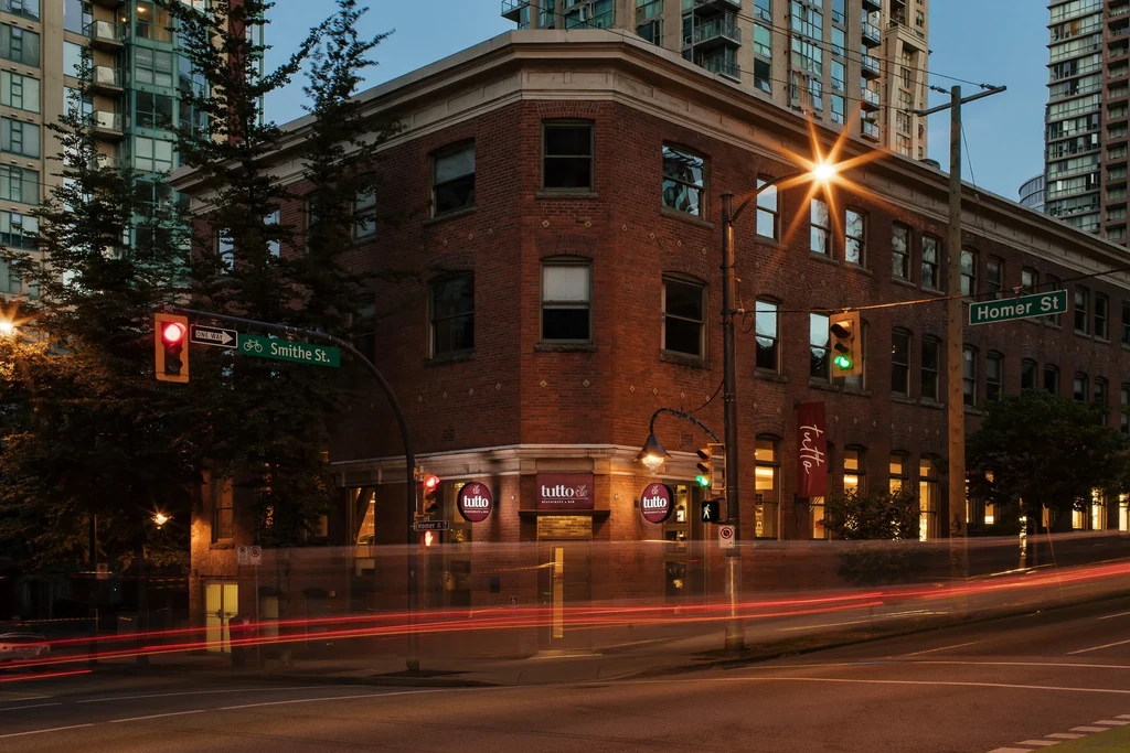Night photo of a brick 'tutto' restaurant with long exposure light trails.