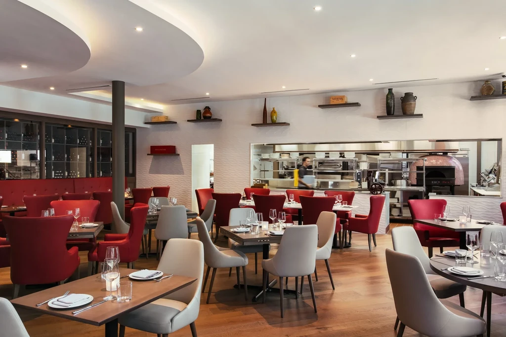 Modern restaurant dining area, open kitchen, and prominent copper pizza oven.