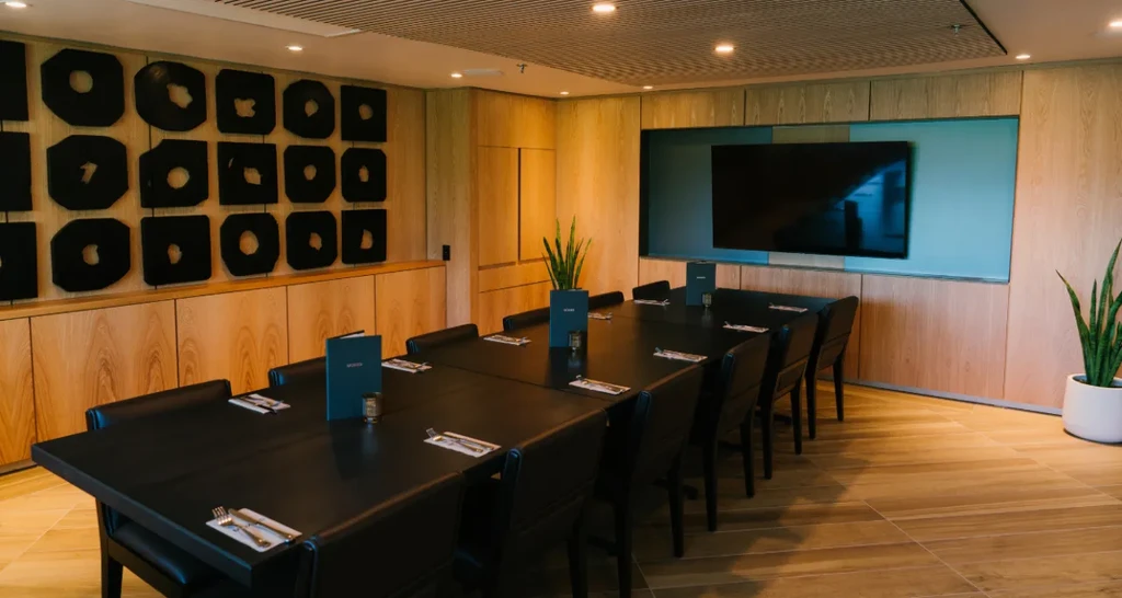 Modern private meeting room with a long table, place settings, and TV.