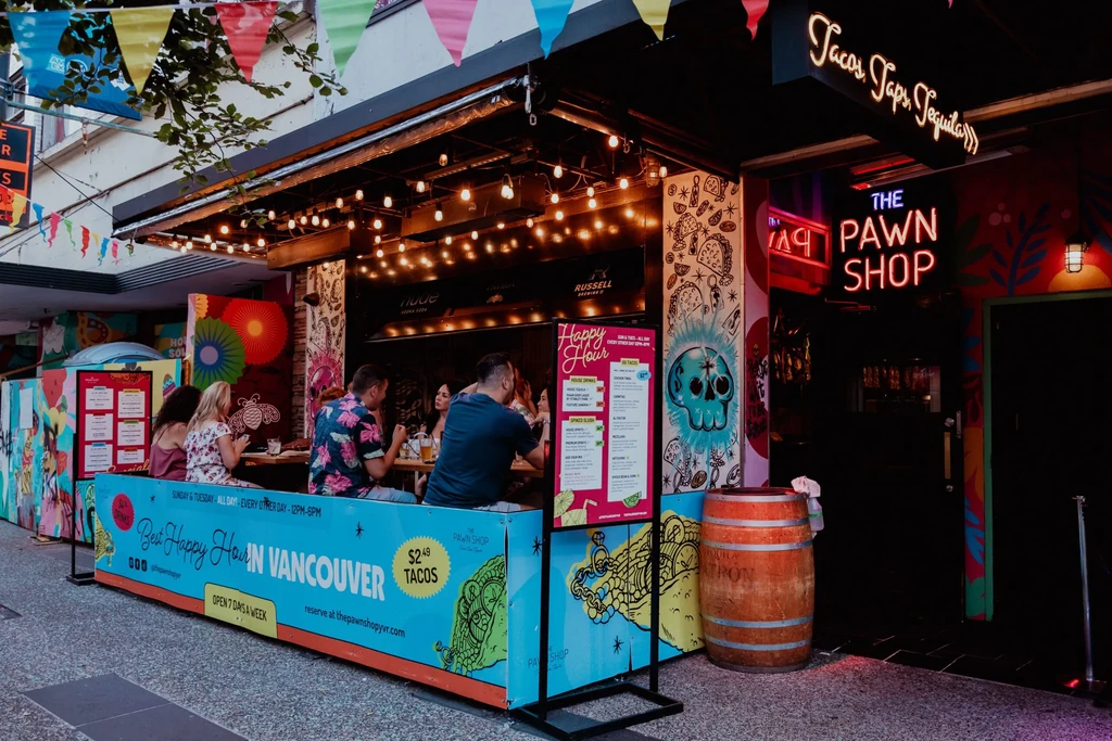 Vibrant outdoor dining area of The Pawn Shop with skull murals.