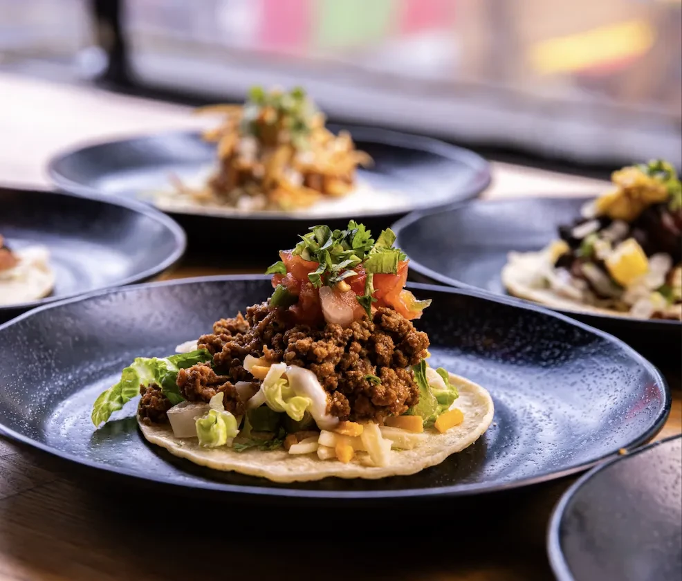 Soft-shell taco with seasoned meat, lettuce, cheese, and pico de gallo.