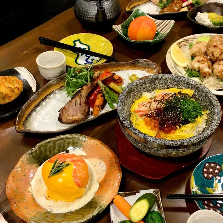 Overhead view of a wooden dining table with many Japanese dishes.
