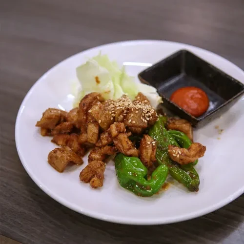 Fried meat with sesame, green peppers, cabbage, and dipping sauce.