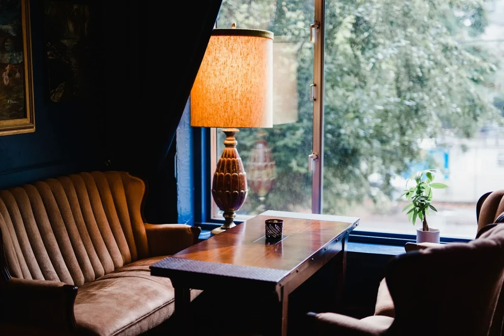 Interior seating area with brown velvet sofa, wooden table, and warm lamp.