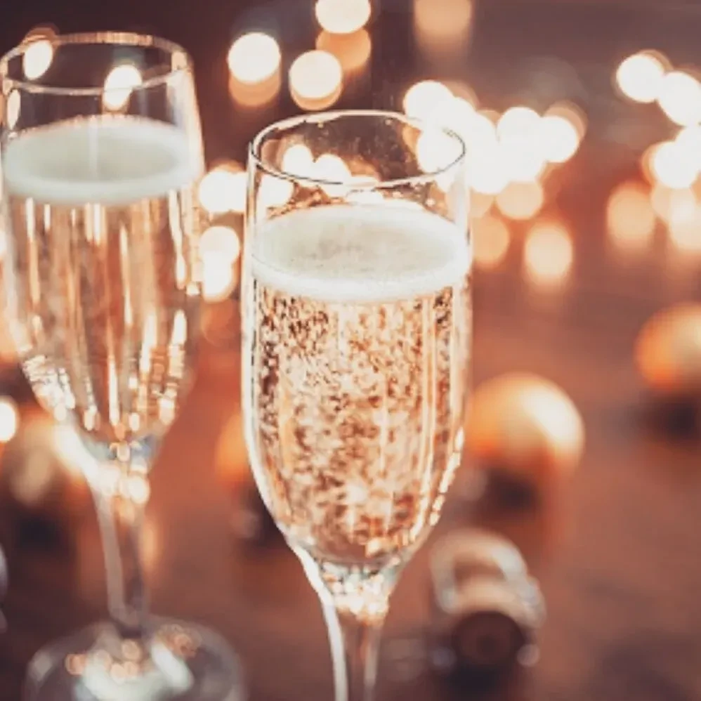 Two champagne flutes with golden sparkling wine and bokeh lights.