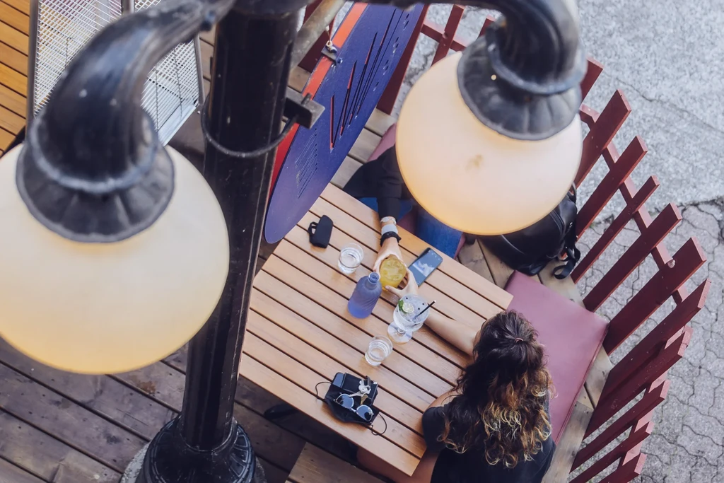 Overhead shot of two people with drinks at an outdoor patio table.