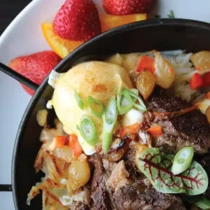 Meat and potato hash, poached egg with hollandaise, and fruit.