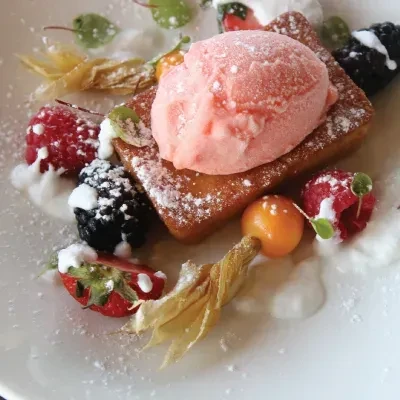 Plated sugared pastry with pink ice cream, berries, and physalis.
