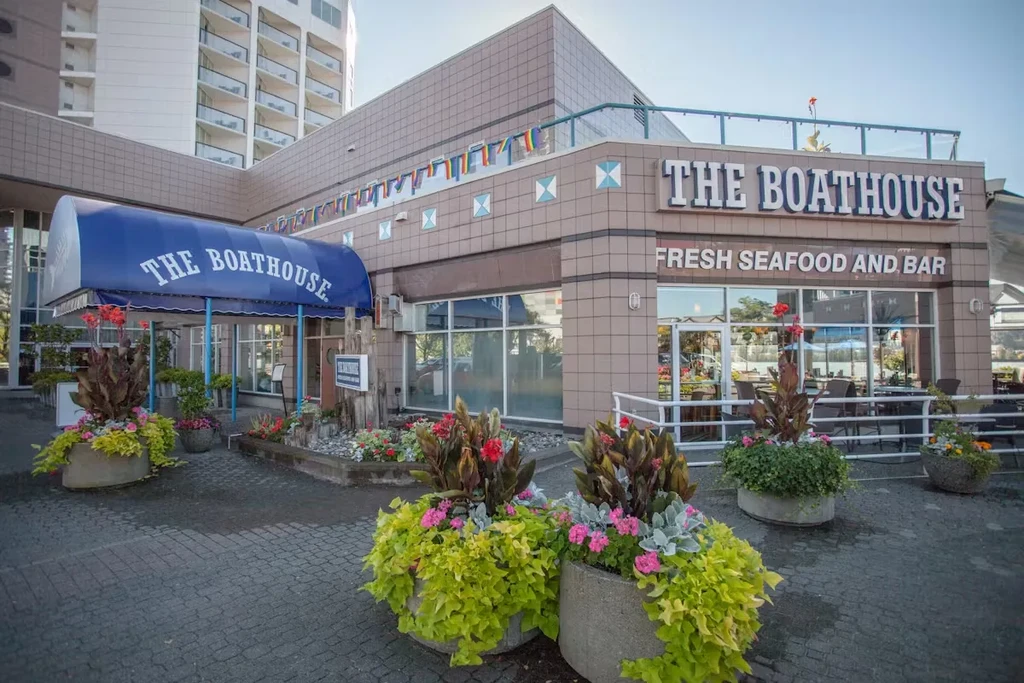 Modern 'THE BOATHOUSE' restaurant exterior, with vibrant flowers and greenery.