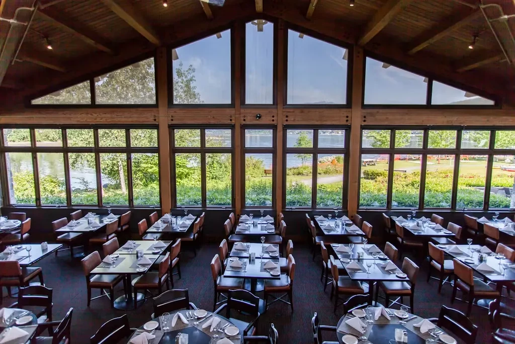 Spacious restaurant with vaulted wooden ceiling and lake view windows.