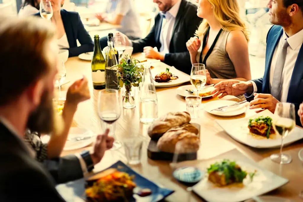 Lively group dining with food and drinks at a modern restaurant.
