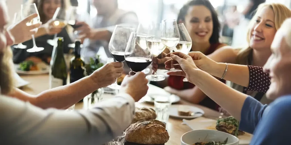 Group of people making a toast with wine glasses at dinner.