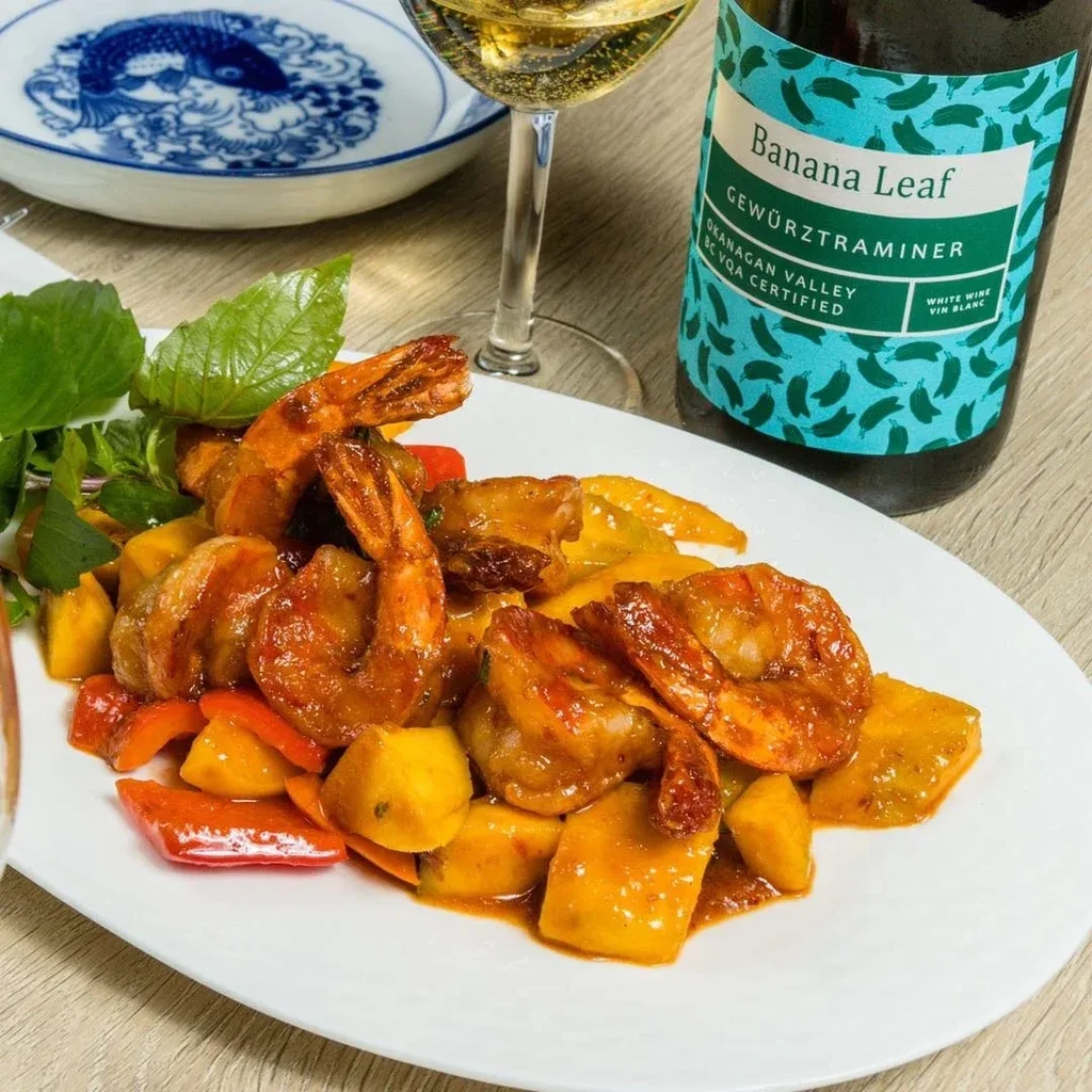 Plated shrimp in reddish sauce, fruit, peppers, and Gewürztraminer wine.