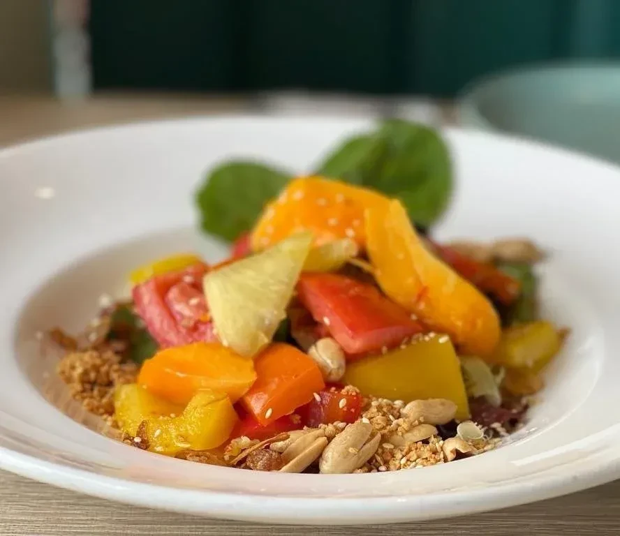 Colorful fruit and nut salad with pineapple, peanuts, and a green leaf.