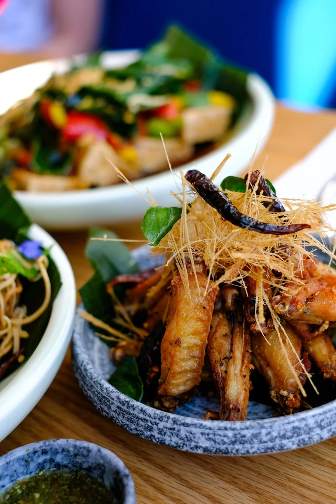 Crispy fried chicken wings, golden herbs, and red chili peppers.