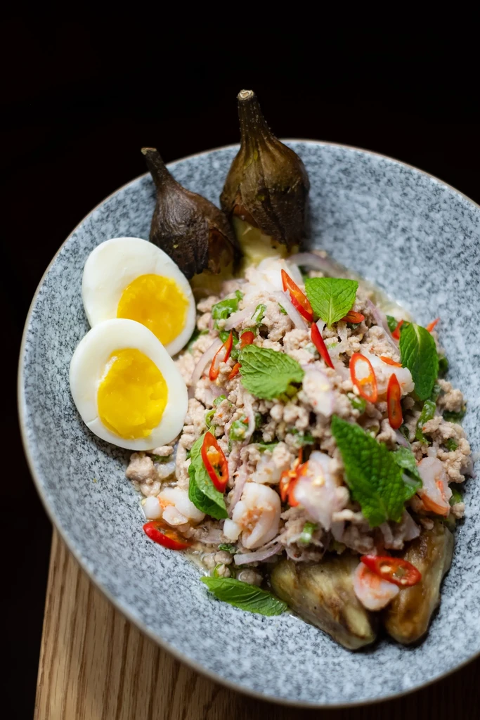 Close-up of artfully presented minced meat salad with shrimp, eggs, eggplant.