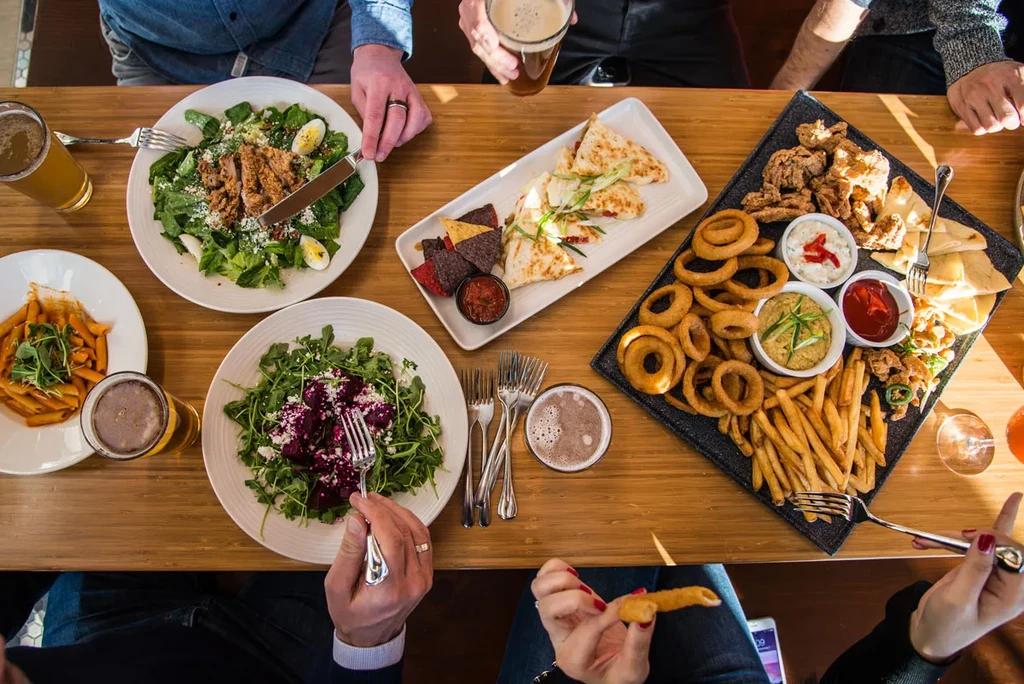 Overhead shot of a table with salads, quesadillas, fried food, and beer.