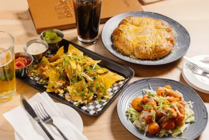 Overhead shot of nachos, baked bread, crispy fried food, and drinks.