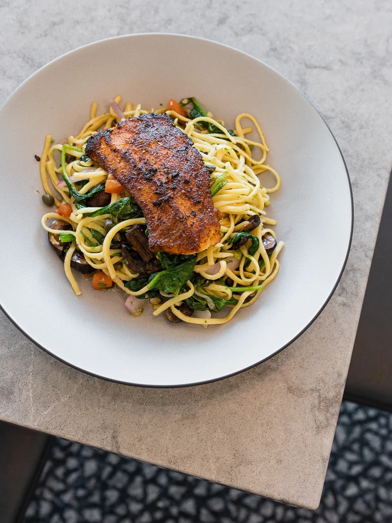 Pan-seared fish on linguine with spinach, tomatoes, and mushrooms.