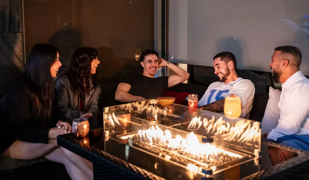 Five people smiling around a restaurant table with a fire pit.