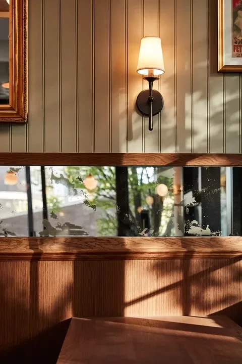 Warmly lit restaurant interior with wainscoting, mirrors, and wooden seating.