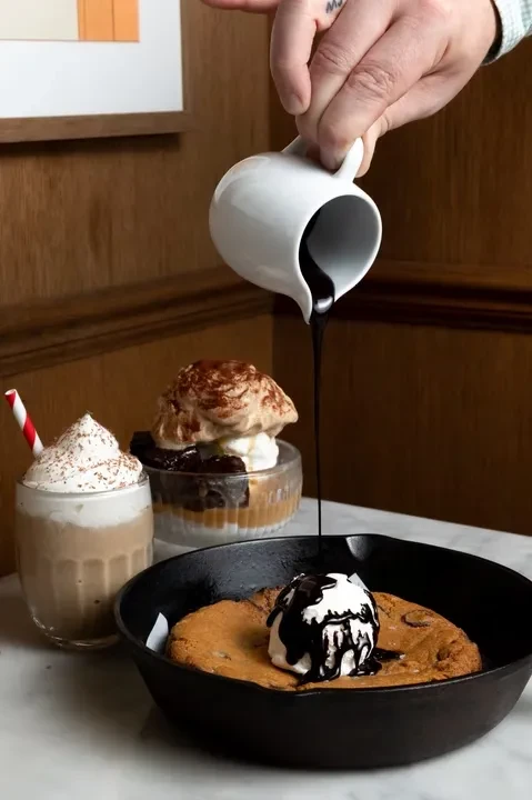 Three desserts: chocolate chip cookie skillet, creamy drink, layered glass dessert.